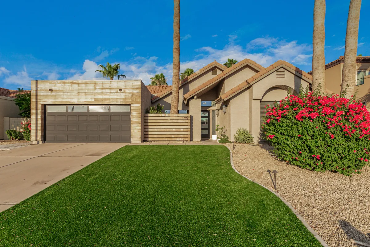 A beautifully landscaped front yard with a lush green lawn, vibrant bougainvillea, and architectural details of the house. The image shows a secure, expansive outdoor area that would be perfect for a pet to play and relax in, with plenty of space for activities.