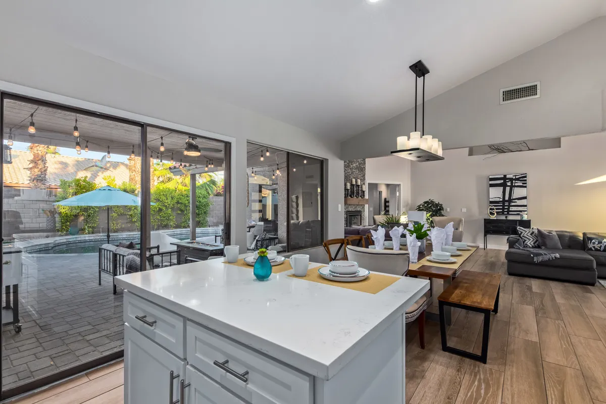 A bright and spacious interior featuring a kitchen island and dining table with a clear view of the pool through large windows. The cohesive indoor-outdoor flow is ideal for family mealtimes and entertaining.